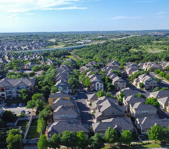 Drone view of residential neighborhoods in Cedar Park, Texas, featuring rows of single-family homes and townhouses surrounded by greenbelt areas—highlighting the family-friendly communities and real estate growth in North Austin suburbs.