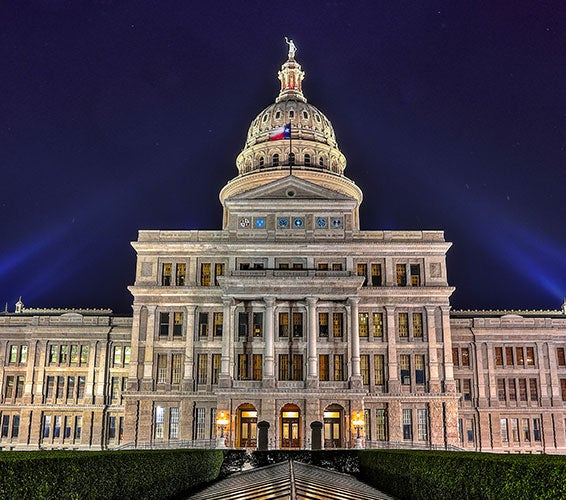 Illuminated night view of the Texas State Capitol in downtown Austin, showcasing its historic architecture, grand dome, and landscaped grounds—an iconic landmark and centerpiece of Central Austin.